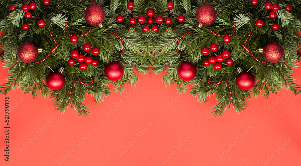 Christmas banner with spruce branches and red bead on the red background. Copy space.