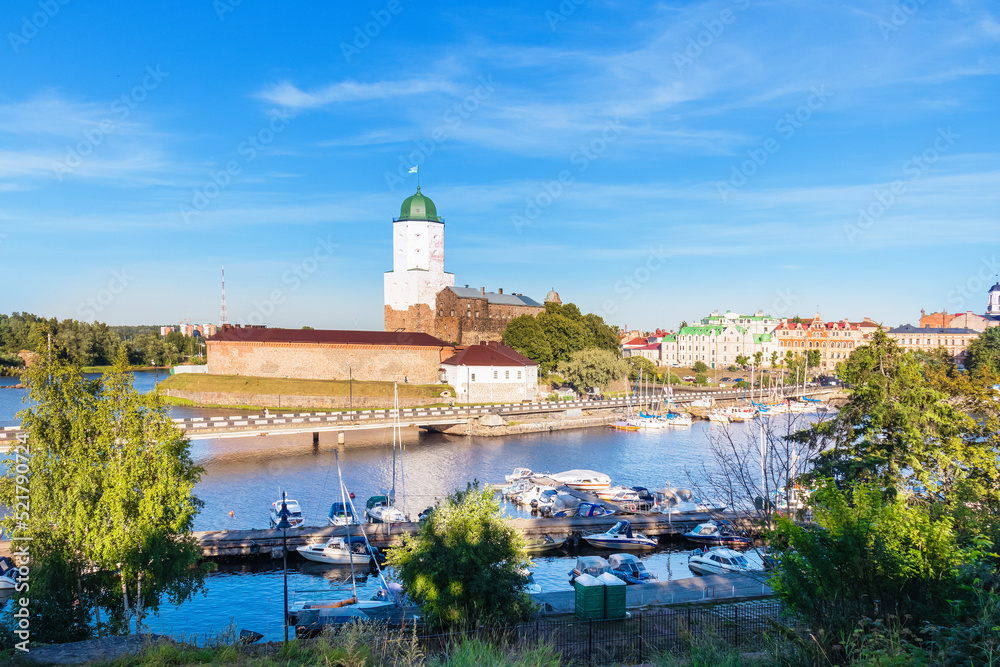 Vyborg castle and pier with boats on sunny day. Famous medieval fortress - Vyborg, Russia, August 2022