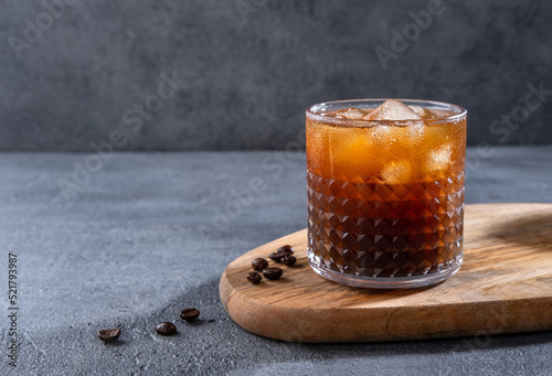 Espresso Tonic, cold drink with espresso and tonic in glass. Ice coffee in a tall glass with cream poured over and coffee beans. Set with different types of coffee drinks on a dark table.