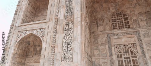 Taj Mahal, islamic ivory-white marble mausoleum, close-up on a historic ornate facade.