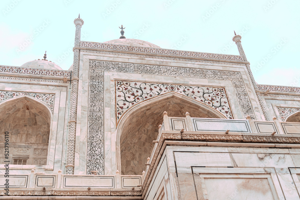 Taj Mahal, islamic ivory-white marble mausoleum, close-up on a historic ornate facade.