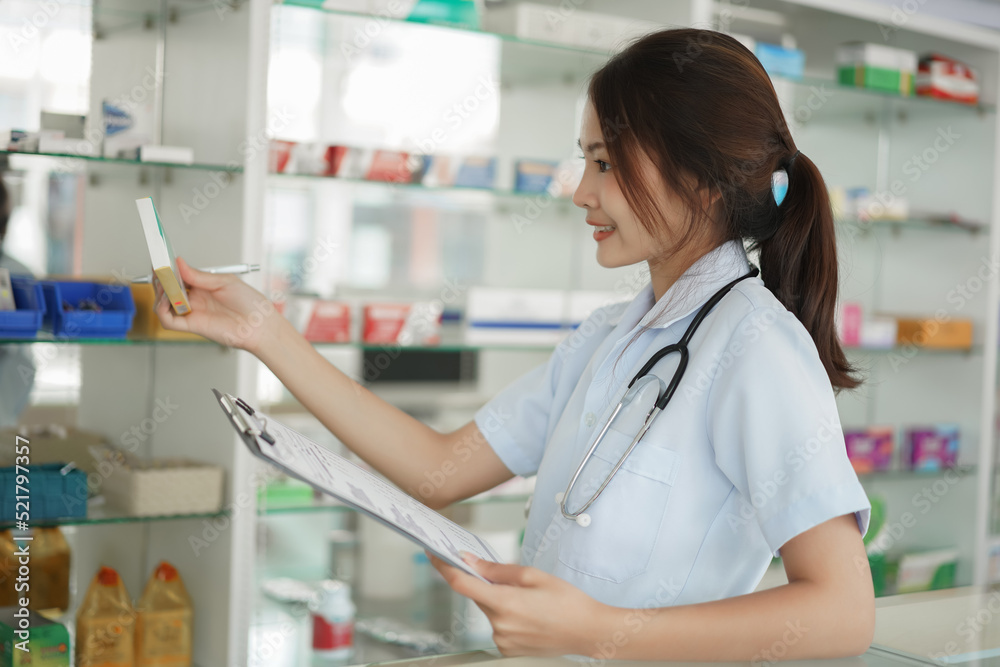 Medicine and health concept, Female pharmacist is holding medicine box and prescription in pharmacy