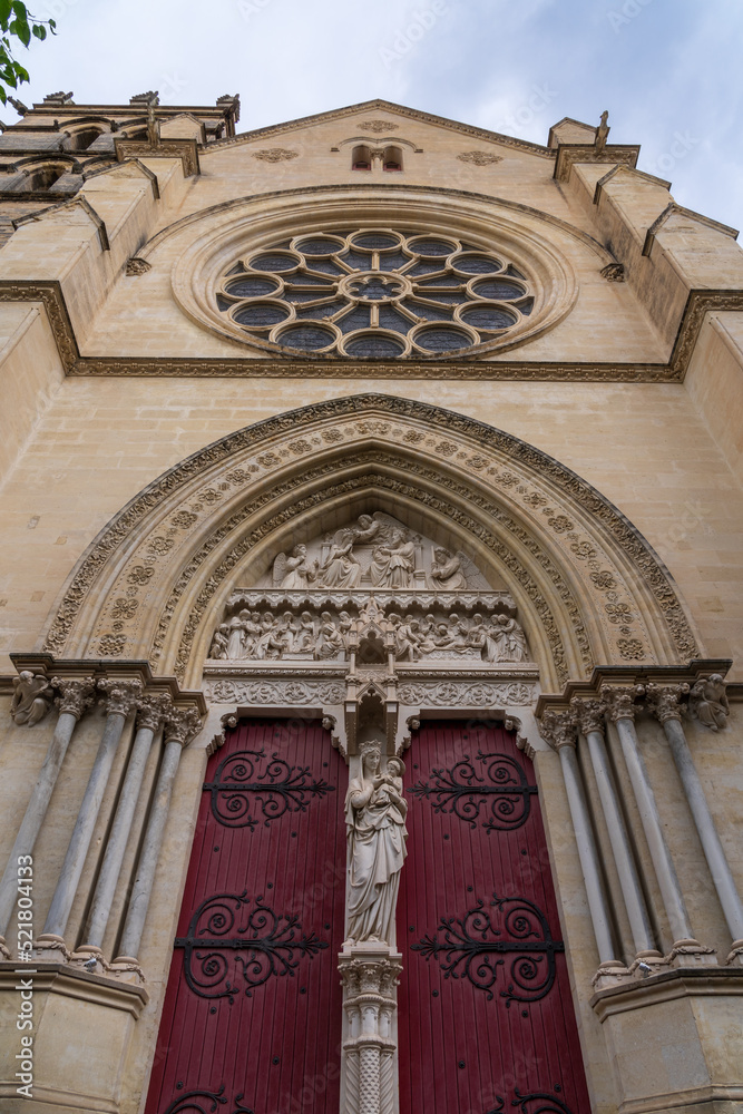 Low angle view of the east entrance to ancient St Pierre or St Peter cathedral dedicated to the Virgin Mary with statue and beautiful tympanum, a tourism landmark of Montpellier, France