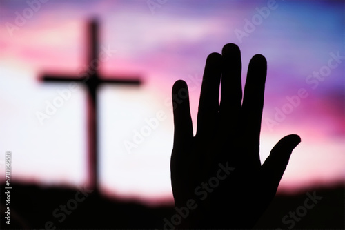 silhouette Hand raising, blurred christian cross background