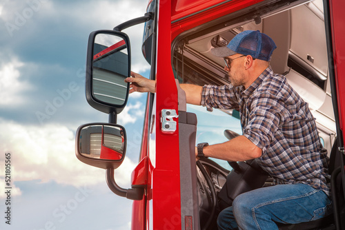 Truck Driver Adjusting Side Mirrors On Semi Truck photo