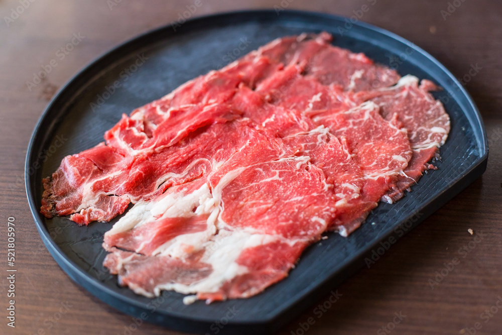 Fresh beef raw sliced was served for Sukiyaki and Shabu or Yakiniku  restaurant which it put on black plate.