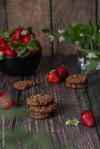Chocolate cookies and ripe strawberries on a wooden table