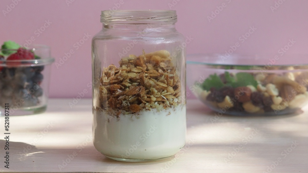 The girl prepares a delicious breakfast with yogurt, muesli, porridge and berries. environmentally friendly products. fresh fruits and berries. vitamins. jar granola The girl prepares a delicious breakfast with yogurt, muesli, porridge and berries. environmentally friendly products. fresh fruits and berries. vitamins. jar granola