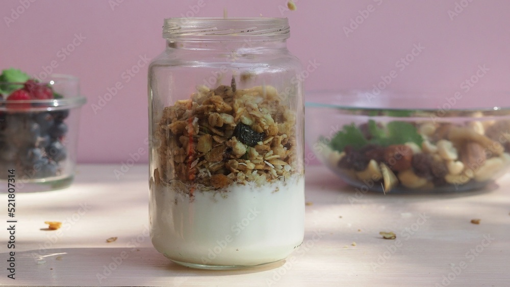 The girl prepares a delicious breakfast with yogurt, muesli, porridge and berries. environmentally friendly products. fresh fruits and berries. vitamins. jar granola The girl prepares a delicious breakfast with yogurt, muesli, porridge and berries. environmentally friendly products. fresh fruits and berries. vitamins. jar granola