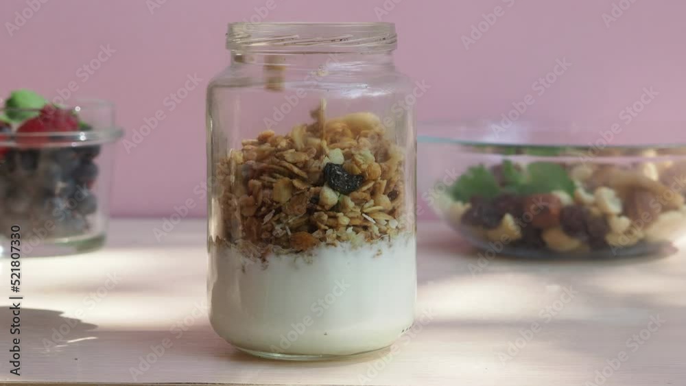 The girl prepares a delicious breakfast with yogurt, muesli, porridge and berries. environmentally friendly products. fresh fruits and berries. vitamins. jar granola The girl prepares a delicious breakfast with yogurt, muesli, porridge and berries. environmentally friendly products. fresh fruits and berries. vitamins. jar granola