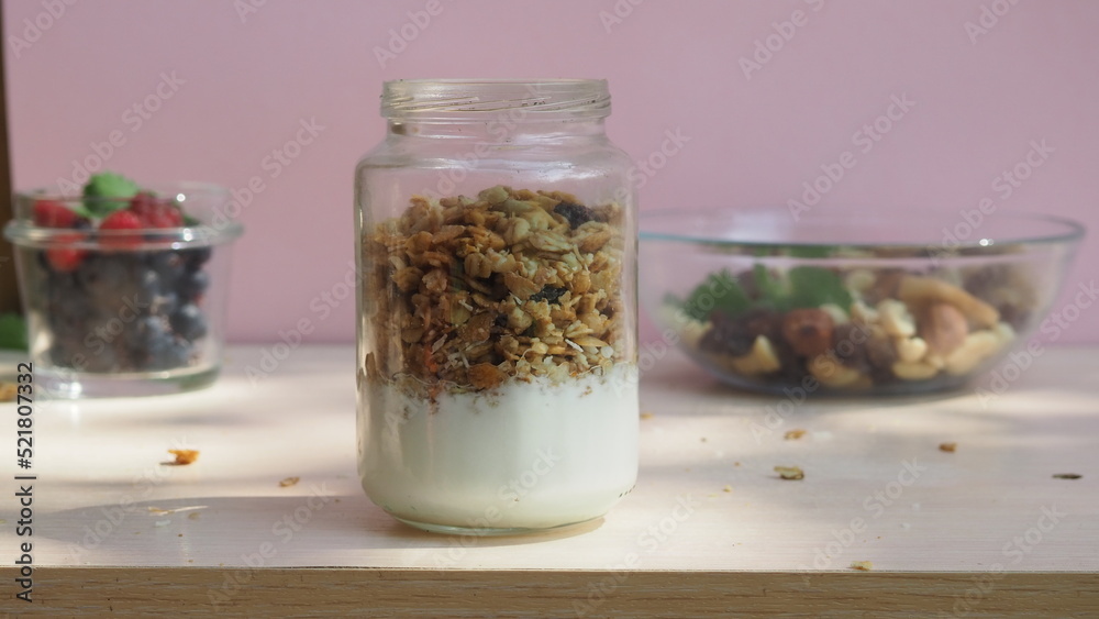 The girl prepares a delicious breakfast with yogurt, muesli, porridge and berries. environmentally friendly products. fresh fruits and berries. vitamins. jar granola The girl prepares a delicious breakfast with yogurt, muesli, porridge and berries. environmentally friendly products. fresh fruits and berries. vitamins. jar granola