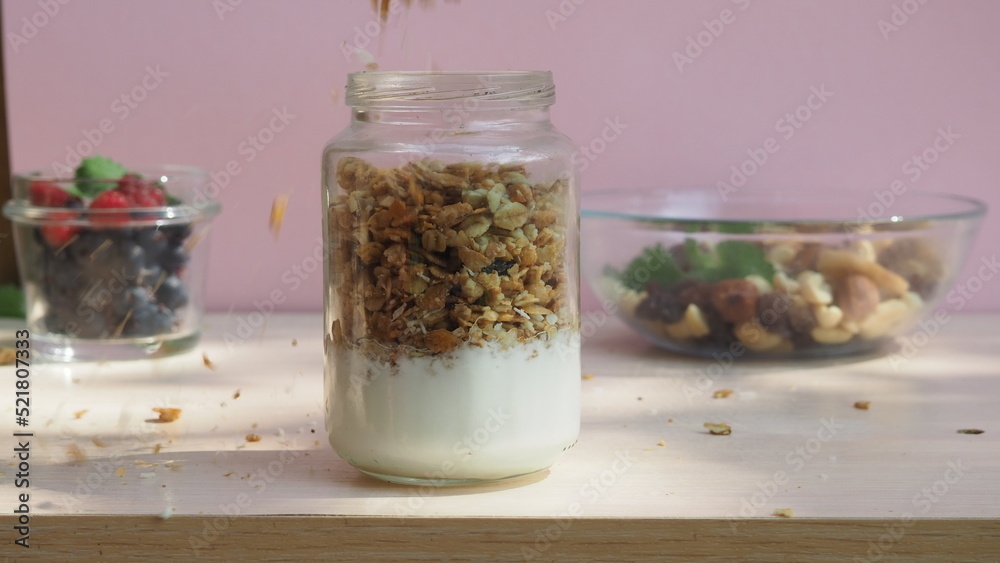 The girl prepares a delicious breakfast with yogurt, muesli, porridge and berries. environmentally friendly products. fresh fruits and berries. vitamins. jar granola