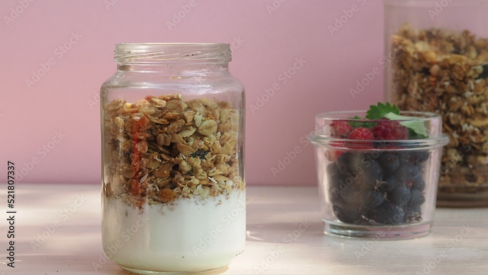 The girl prepares a delicious breakfast with yogurt, muesli, porridge and berries. environmentally friendly products. fresh fruits and berries. vitamins. jar granola The girl prepares a delicious breakfast with yogurt, muesli, porridge and berries. environmentally friendly products. fresh fruits and berries. vitamins. jar granola