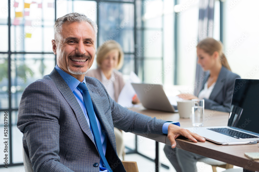 Businessman with colleagues in the background in office. Businessman with colleagues in the background in office.