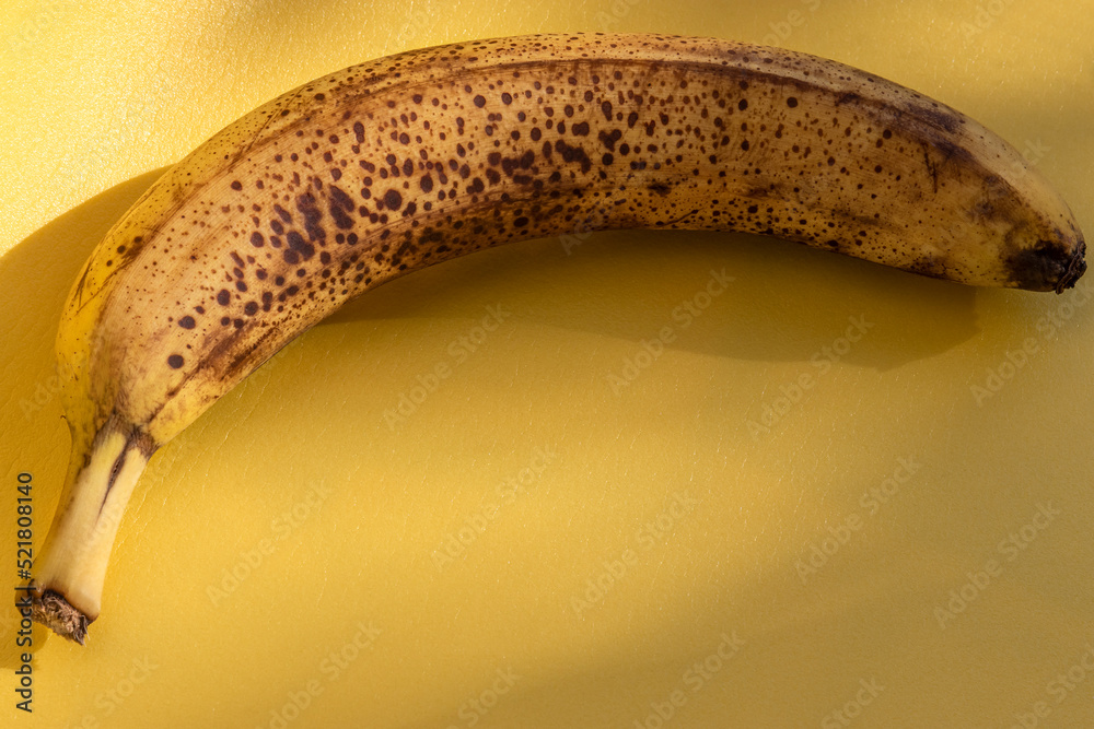 Overripe banana on yellow background, close-up. Long-term storage. Topic: storage of perishable products, shelf life. Spectacular background on topic of violations in shelf life of products