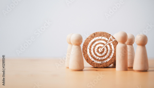 Wooden miniature figures standing with dartboard and arrow for setup business objective target and goal concept. photo