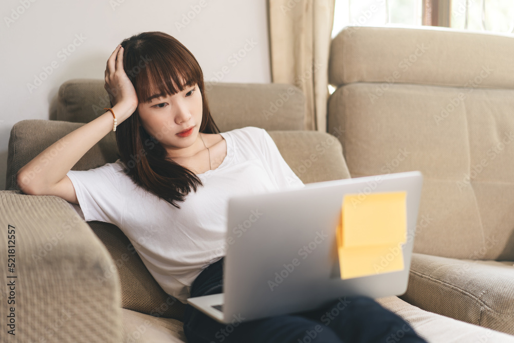 Young adult asian woman using laptop laying on sofa for telemedicine mental health or shopping online Young adult asian woman using laptop laying on sofa for telemedicine mental health or shopping online