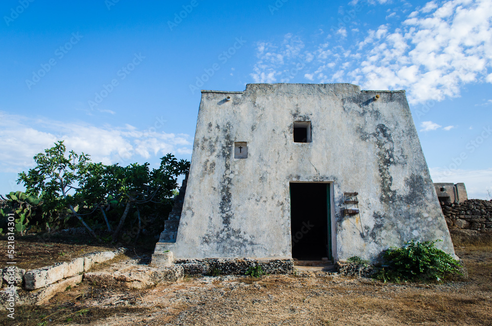 Un'antica masseria abbandonata con dietro degli ulivi nella campagna del Salento, in Puglia