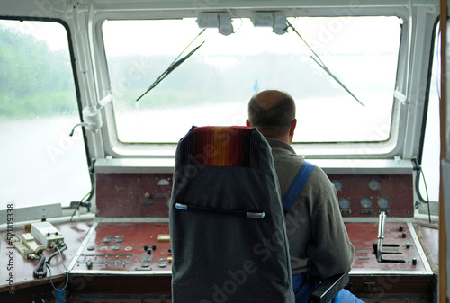 Man helmsman driving the pleasure boatboat in the wheelhouse. Chernigiv, Ukraine photo