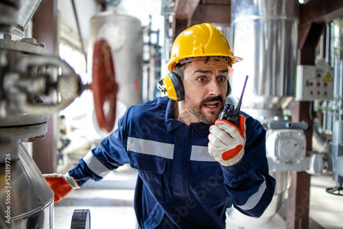 Factory worker in panic using radio communication to alert about fire and explosion in refinery production plant. Problems at work.