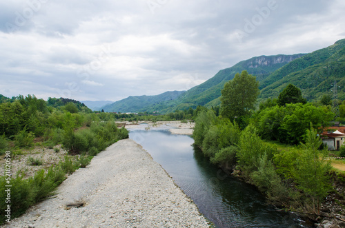 Il panorama di un fiume lungo la Via del Volto Santo, cammino che parte da Pontremoli e arriva a Lucca, con un cielo nuvoloso