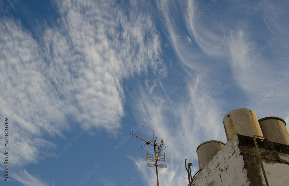 Antenna and water barrels on the roof of a house and cloudscape. Las Palmas de Gran Canaria. Gran Canaria. Canary Islands. Spain.