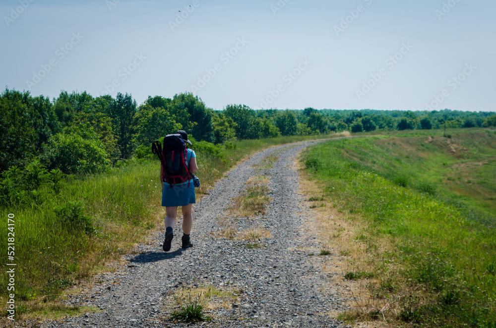 Una pellegrina cammina in un campo lungo la Via degli abati, cammino che parte da Pavia e arriva a Pontremoli