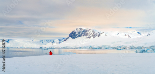 Antarktis Tourist in rotem Parka vor antarktischer Eisberg Landschaft bei Portal Point welches am Zugang zu Charlotte Bay auf der Reclus Halbinsel, an der Westküste von Graham Land liegt
