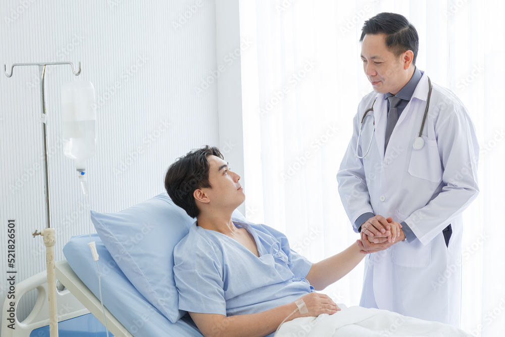 Senior doctor and young male patient who lie on the bed while checking pulse, consult and explain with nurse taking note and supporting in hospital wards. Senior doctor and young male patient who lie on the bed while checking pulse, consult and explain with nurse taking note and supporting in hospital wards.