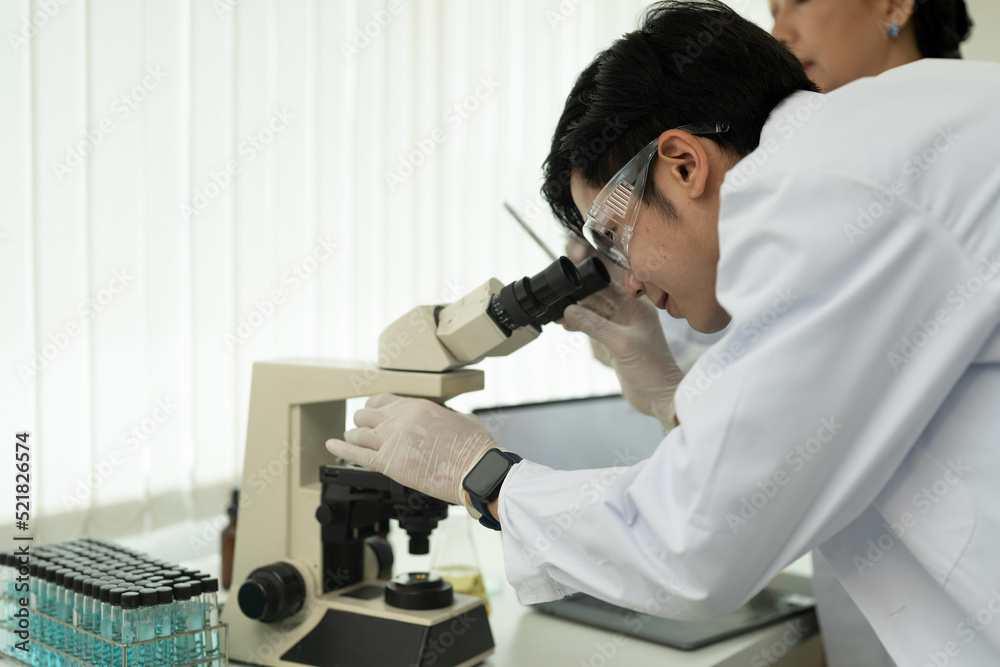 Scientist Looking Under Microscope Does Analysis of Test Sample. Ambitious Young Biotechnology Specialist, working with Advanced Equipment. Scientist Looking Under Microscope Does Analysis of Test Sample. Ambitious Young Biotechnology Specialist, working with Advanced Equipment.