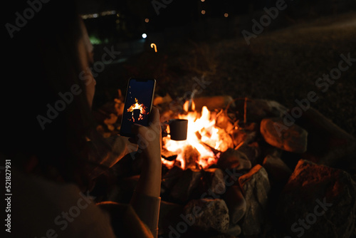 Woman takes a picture of a mug near the campfire. Close up. © scharfsinn86
