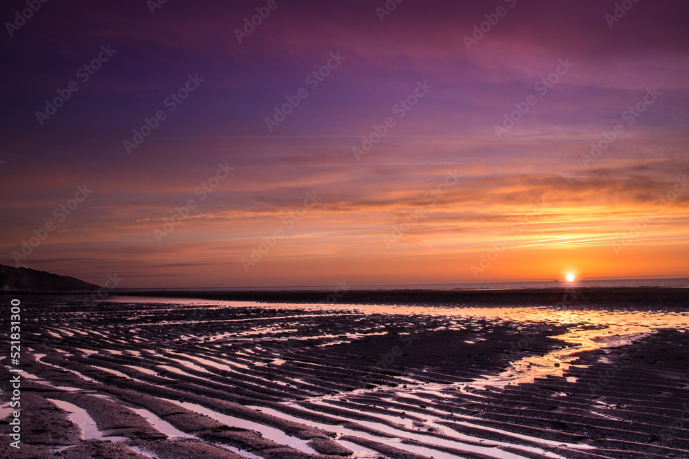 Colorful sunset on the Atlantic coast at low tide in Normandy, France Colorful sunset on the Atlantic coast at low tide in Normandy, France