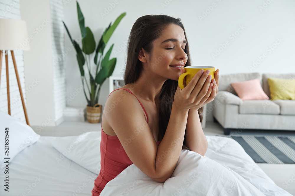 Attractive young woman enjoying coffee after waking up in bed Attractive young woman enjoying coffee after waking up in bed