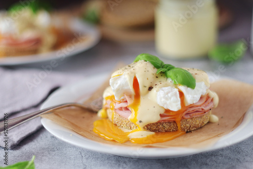 Egg benedict sandwiches - muffin with poached egg, ham and hollandaise sauce