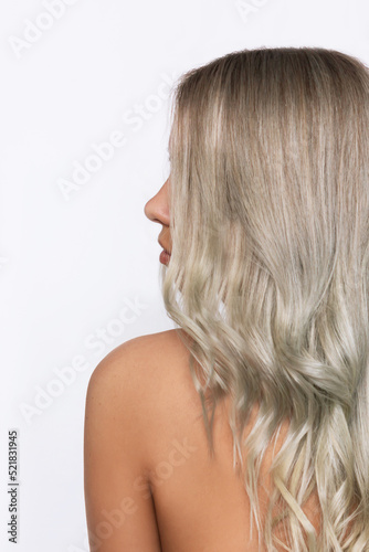 Close-up of the wavy blonde hair of a young blonde woman isolated on a white background. Result of coloring, highlighting, perming. Beauty and fashion. Vertical shot