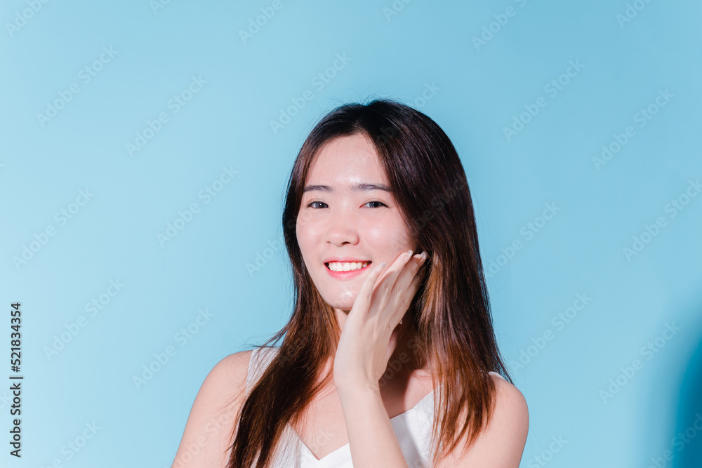 Charming asian beauty woman hold sun cream with sun protection uv or sunscreen on the blue background Charming asian beauty woman hold sun cream with sun protection uv or sunscreen on the blue background