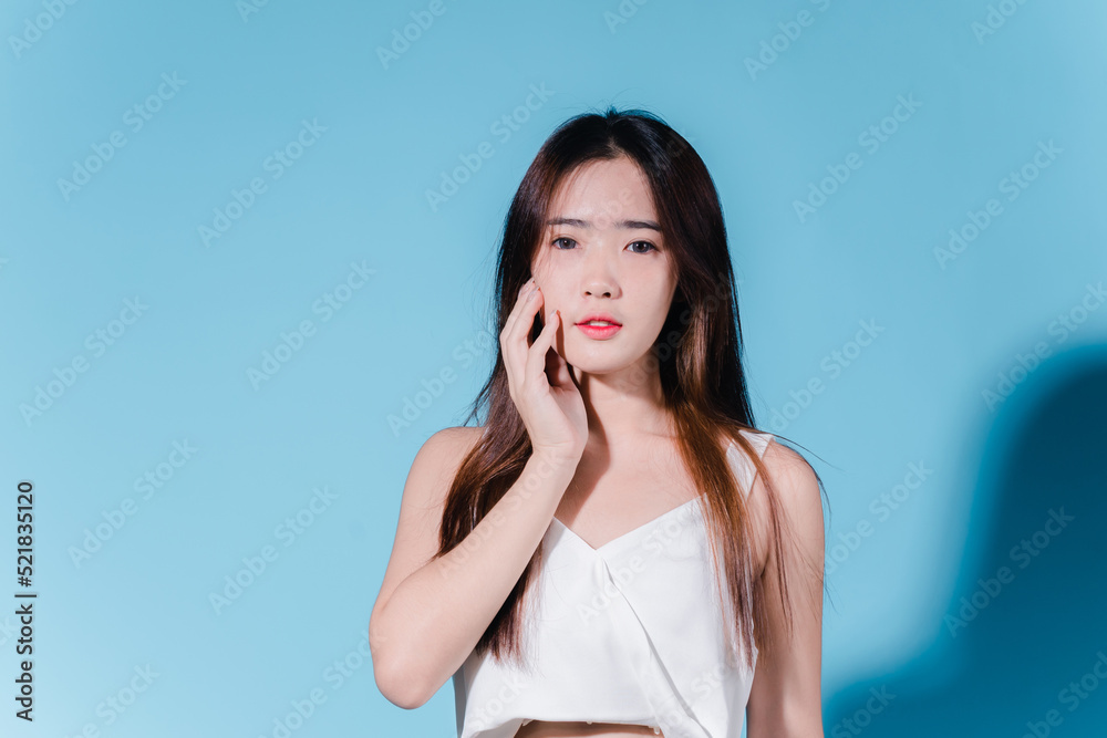 Charming asian beauty woman hold sun cream with sun protection uv or sunscreen on the blue background Charming asian beauty woman hold sun cream with sun protection uv or sunscreen on the blue background