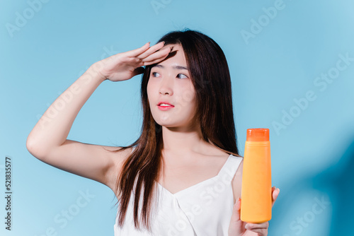 Charming asian beauty woman hold sun cream with sun protection uv or sunscreen on the blue background