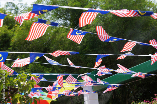 SELANGOR, MALAYSIA -AUGUST 31, 2021: Several small Malaysian flags are tied together and installed horizontally. These flags flutter when the wind blows.