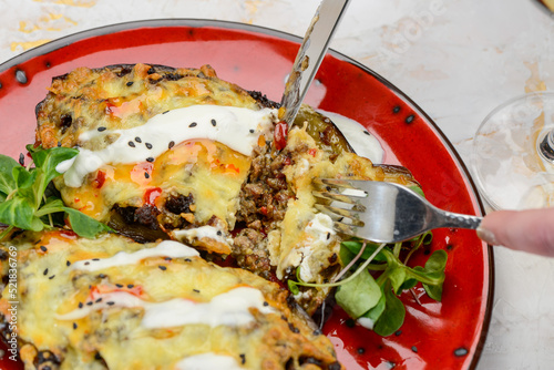 stuffed eggplants under cheese in a red plate, macro photo
