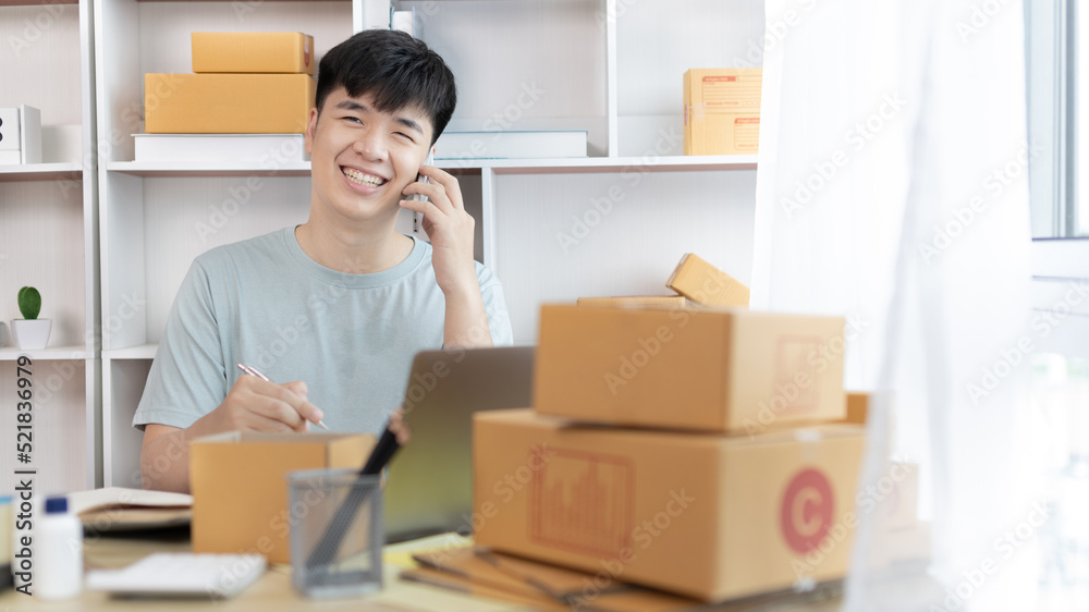 Man selling products online was talking on the phone or chat to receive an order from a customer and list in a notebook, Online shopping SME entrepreneur, Packing box, Sell online, Freelance working. Man selling products online was talking on the phone or chat to receive an order from a customer and list in a notebook, Online shopping SME entrepreneur, Packing box, Sell online, Freelance working.