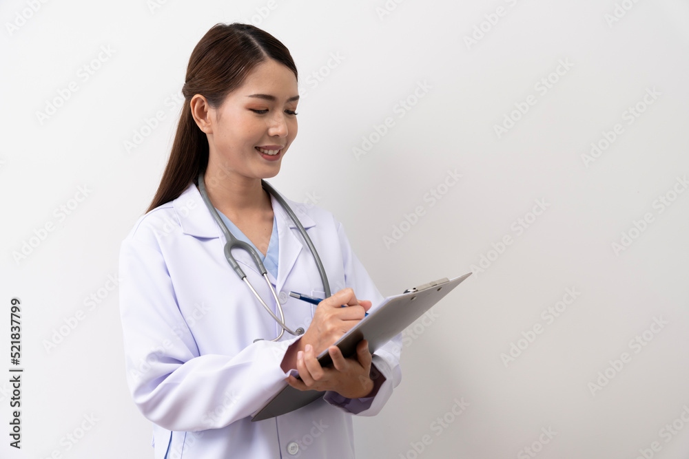 A long-haired brown-haired Asian female doctor in a white medical uniform smiling brightly, is standing with a paper board isolated against the background. A long-haired brown-haired Asian female doctor in a white medical uniform smiling brightly, is standing with a paper board isolated against the background.