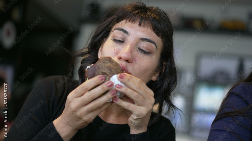 One hispanic woman eating burger. A latin american girl eats fast food cheeseburger One hispanic woman eating burger. A latin american girl eats fast food cheeseburger