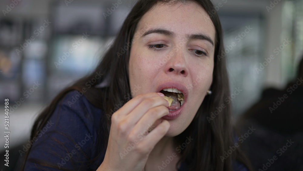 Woman eating french fries and hamburger. Person eats fast food for lunch takes a bite of burger at restaurant Woman eating french fries and hamburger. Person eats fast food for lunch takes a bite of burger at restaurant