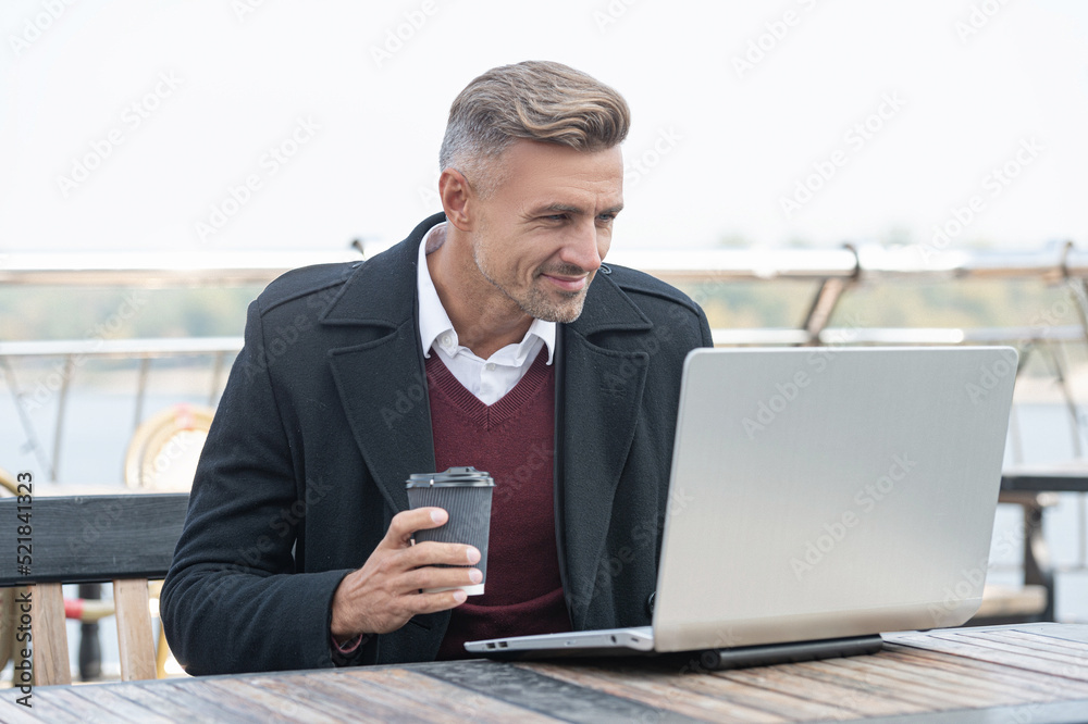 Happy man blogger in formalwear blogging business blog in laptop drinking coffee in outdoor cafe Happy man blogger in formalwear blogging business blog in laptop drinking coffee in outdoor cafe