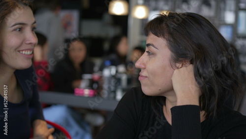 Two women talking at restaurant. Female friends sharing gossip in conversation at cafe