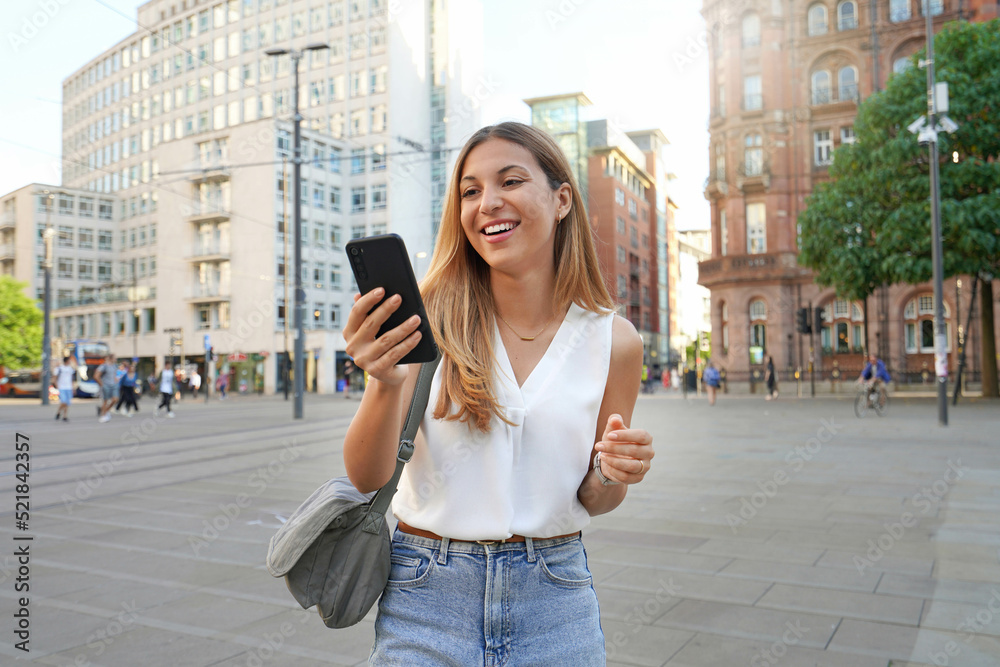 Fototapeta premium Attactive business woman watching her smartphone walking in the city Manchester, UK