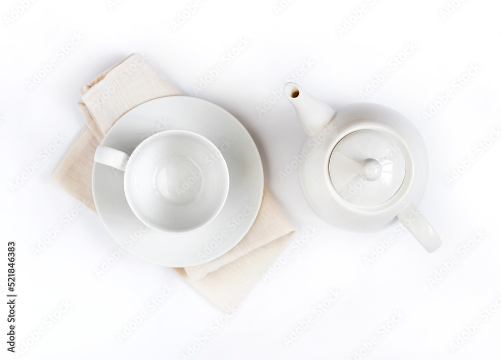 Teapot and empty teacup on pale beige cloth isolated on white background