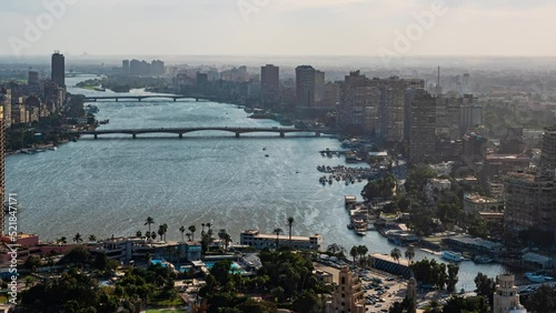 Top view of modern Cairo, river Nile, island Gezira. Timelapse. Daily life in capital of Egypt with buildings, trees, skyscrapers, cars, boats. Sunlight and clouds over the city