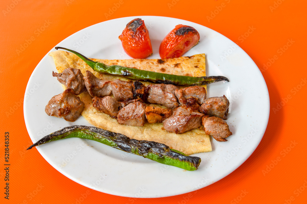 A skewered chicken kebob with grilled onions, bell peppers and delicious white meat with seasoning isolated on a white background. Tavuk sis, Tavuk izgara.